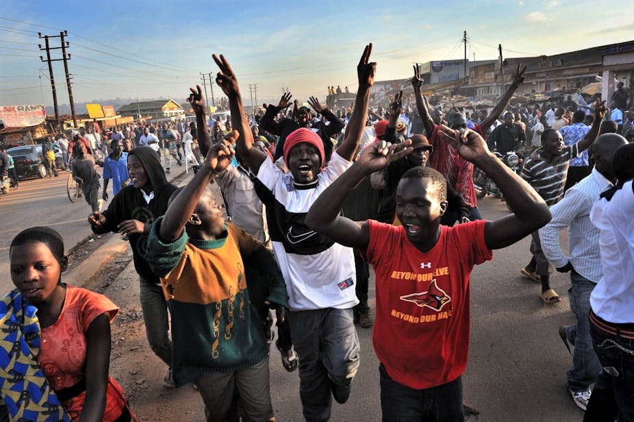 A crowd of young people in the street, their arms raised