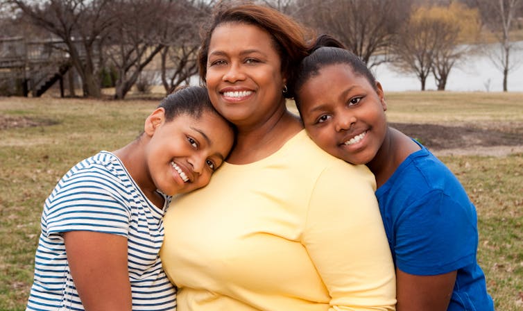 Two sisters and mother hugging