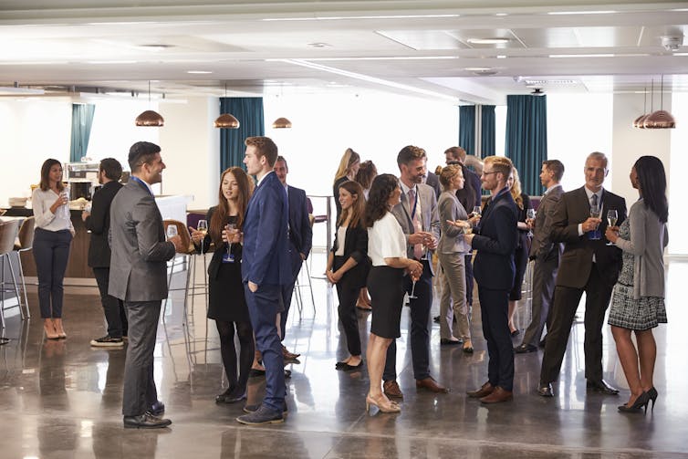 People stand networking at a conference