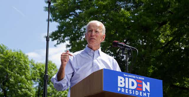 Joe Biden delivers a speech at a podium outside.
