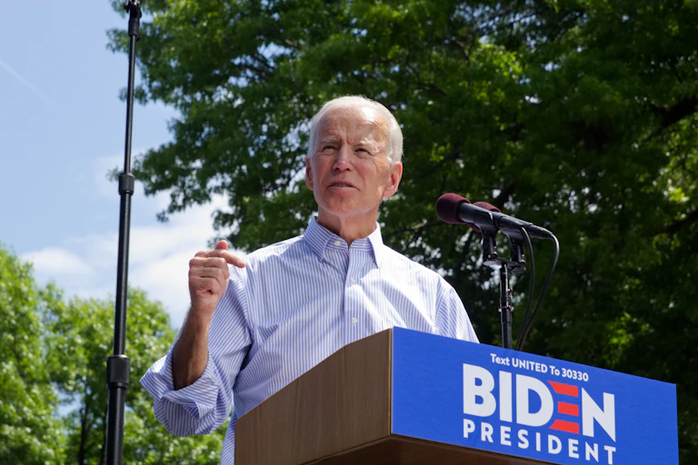 Joe Biden delivers a speech at a podium outside.