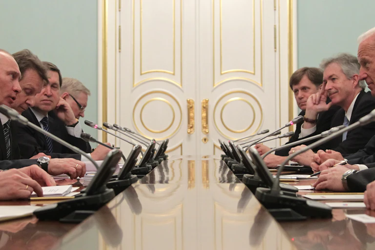 Vladmir Putin and advisors sitting across table from Joe Biden and advisors