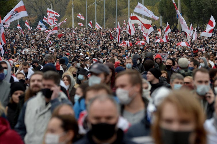 People protesting on the street with red and white flags.