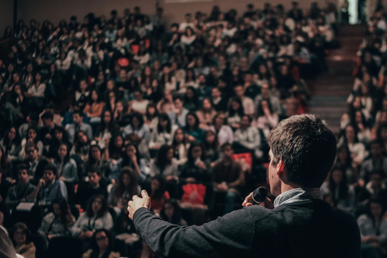 A man I seen from behind speaking to a lecture theatre audience