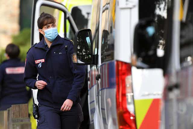 A paramedic wearing a mask next to an ambulance