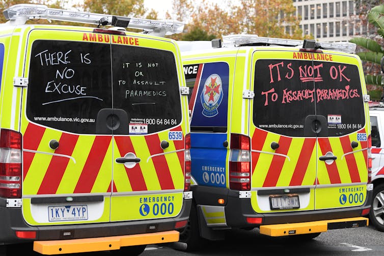 Two ambulances featuring written messages about how it's never OK to assault paramedics