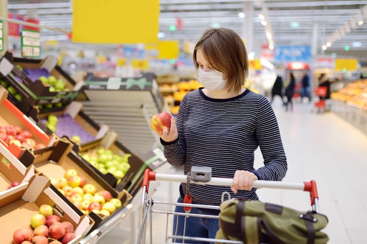 A woman wears a mask in the supermarket.