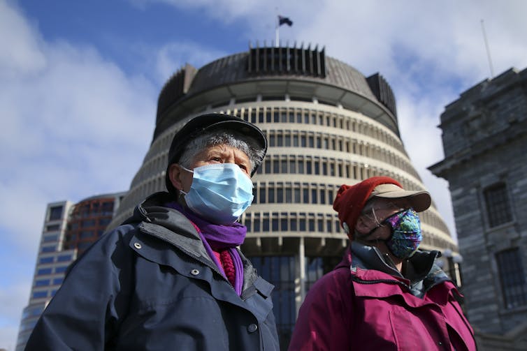 Two women wearing masks outside New Zealand's parliament building in Wellington.