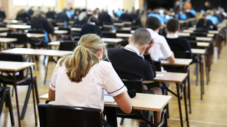 Students in uniform sitting in exam hall facing away