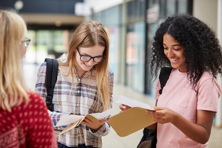 Female students opening their exam result envelopes