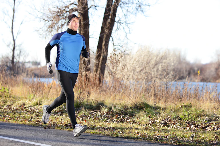 Young man running outdoors on a cold, sunny Autumn or winter day.