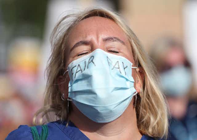 WOman wearing face mask demanding fair pay.