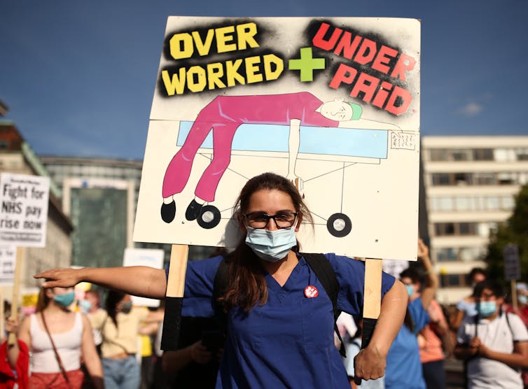 NHS worker with a placard demanding fair pay.