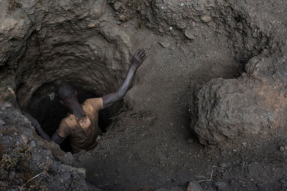A man, seen from above, getting into a hole in the ground 