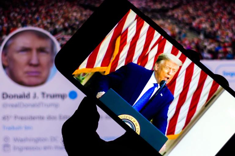 Smart phone with a video of Donald Trump with his Twitter bio in the background.