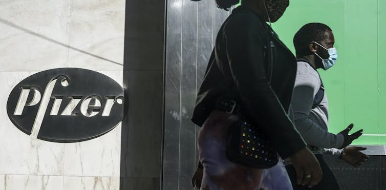 People wearing masks walk in front of Pfizer’s headquarters in New York City. 