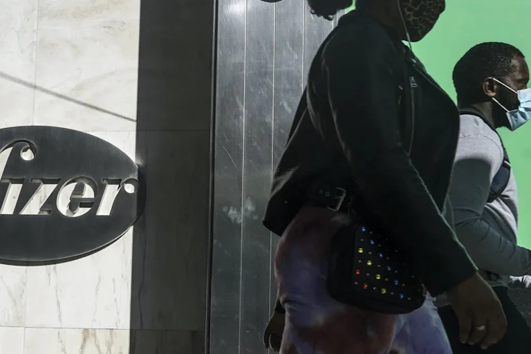 People with masks in front of Pfizer headquarters