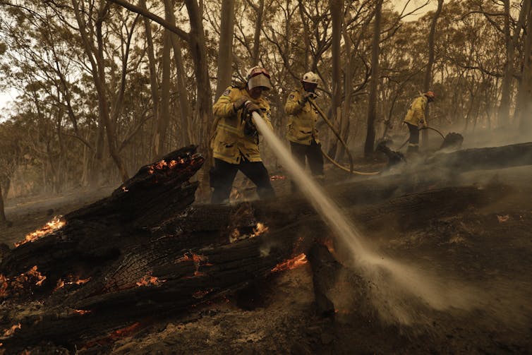 A firefighter hosing down spot fires.