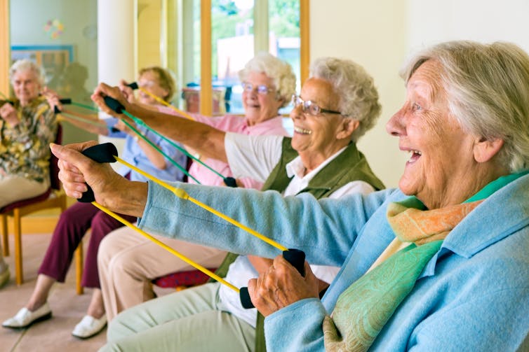 Elderly people in a nursing home doing group exercise sitting down