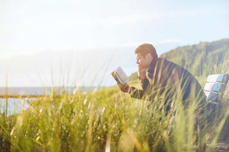 Man reads book on park bench