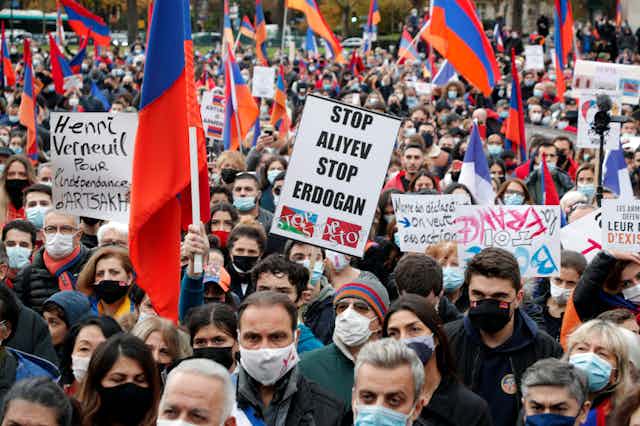 Demonstrators in Paris wearing masks and holding signs in French and English protesting the Nagorno-Karabakh conflict.