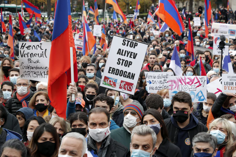 Demonstrators in Paris wearing masks and holding signs in French and English protesting the Nagorno-Karabakh conflict.