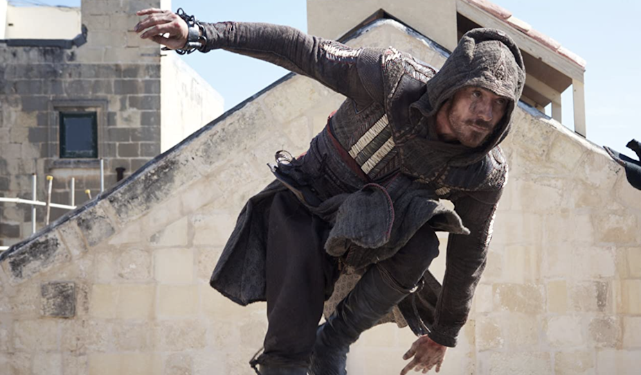 Michael Fassbender jumping over a wall dressed as a medieval assasin.