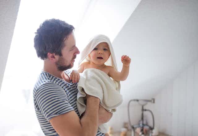 Un hombre seca a un bebé tras el baño.