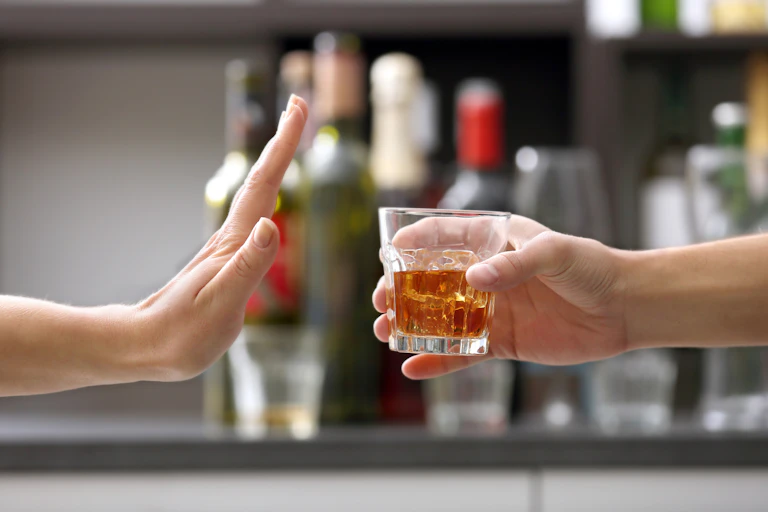 Una mano rechazando un vaso de alcohol.