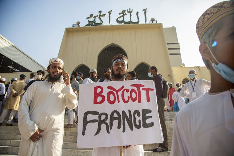 A young man holds up a sign reading 'boycott France'
