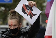 A young woman holds up a sign as she protests.