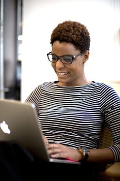 A woman sits with a laptop in a videoconference.