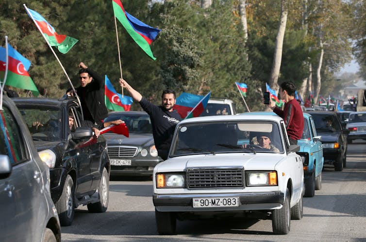 Parade of cars with men waving Azerbaijani flags out the windows