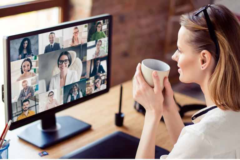 Young woman drinking coffee as she takes part in an online group chat