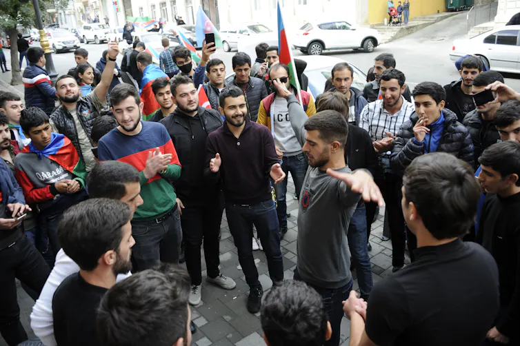 A group of Azeri men stand by as one performs a celebration dance.