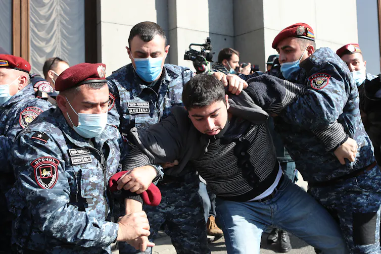 A group of Armenian security officers detain a protestor.
