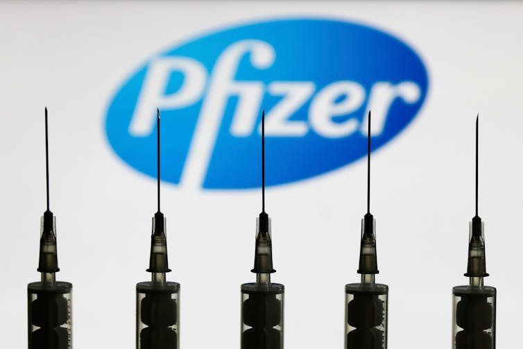 Syringes in front of Pfizer logo.