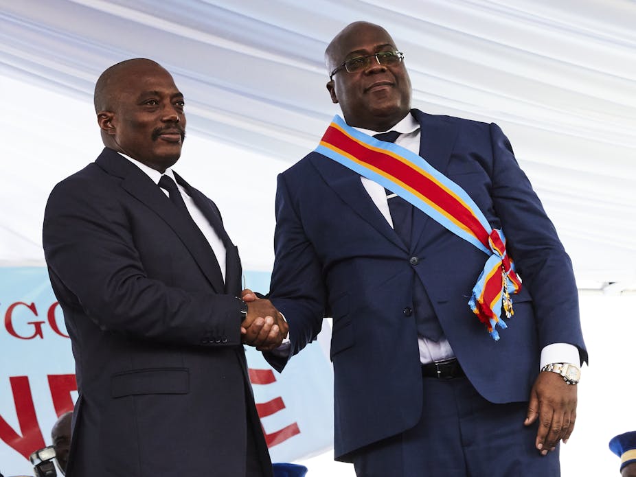 Former DRC President Joseph Kabila, left, shakes hands with his successor Felix Tshisekedi at his inauguration. Both men are wearing navy-blue suits.