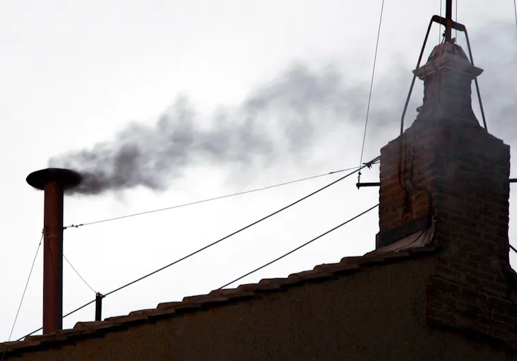 Black smoke pours out of a chimney on the Vatican roof as cardinals canvass for the next pope.