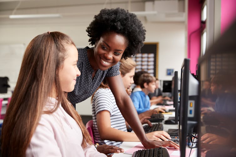 Teacher smiling at pupil in computer class