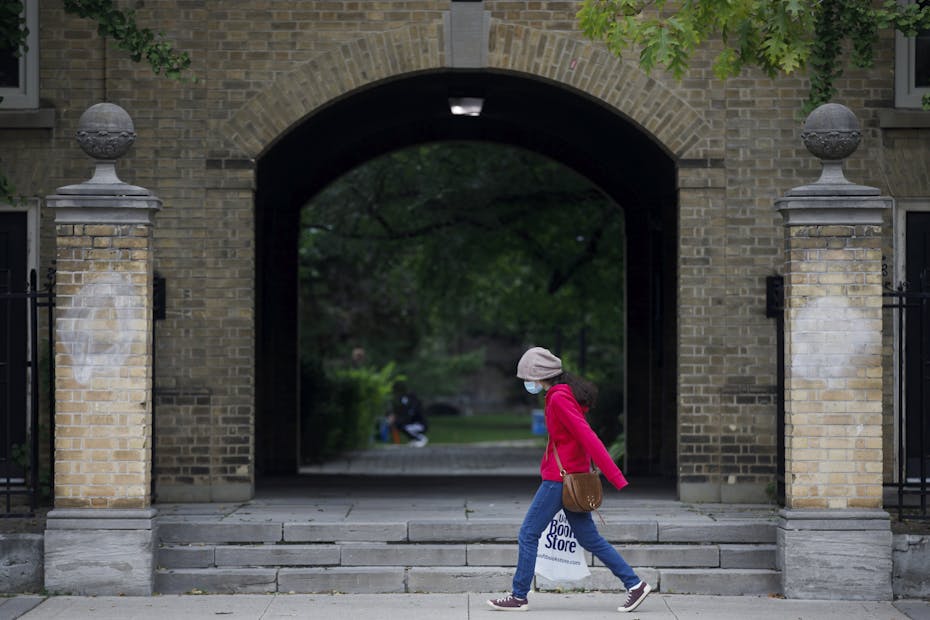 A person walks by carrying a university building.