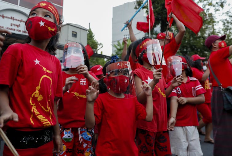 Children wearing political t-shirts and waving banners celebrate victory in the Myanmar election, November 2020.