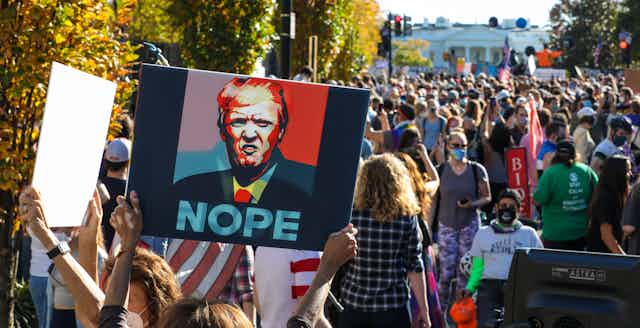 Un manifestante porta un cartel con el rostro de Donal Trump y la leyenda 'NOPE'.