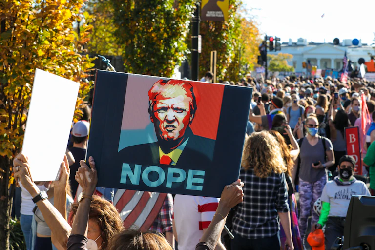 Un manifestante porta un cartel con el rostro de Donal Trump y la leyenda 'NOPE'.
