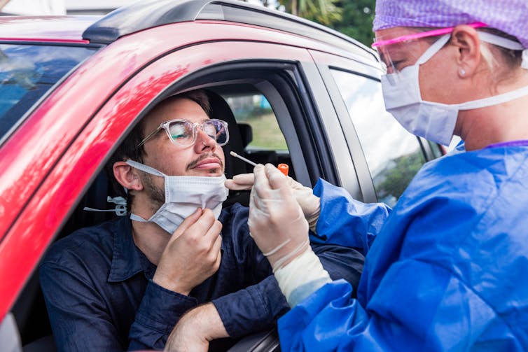 A young man in his car gets a COVID test.