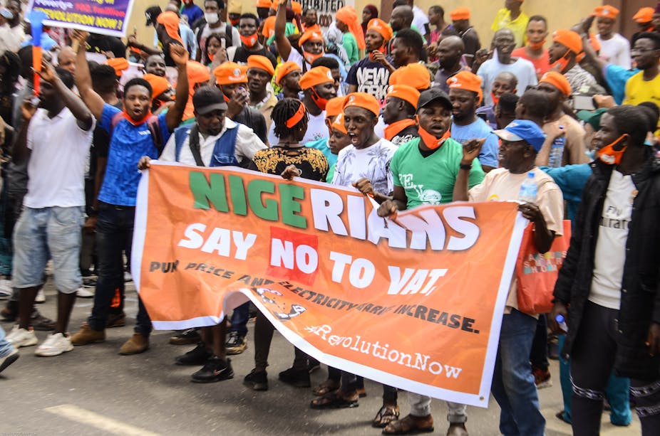 Members of the Revolution Now group, mostly in yellow caps, holding a banner demanding for better governance in Nigeria during a protest in Lagos to mark the country's 60th Independence Day in October 2020. 