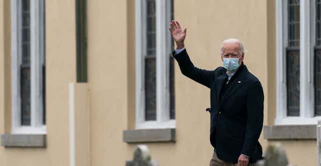 Joe Biden waving wearing a mask.