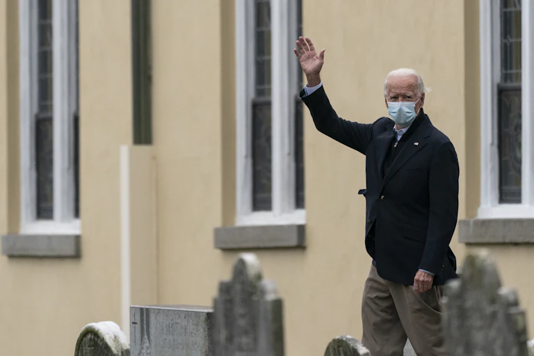Joe Biden waving wearing a mask.