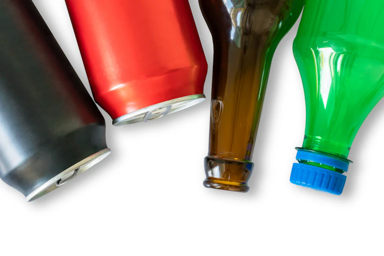 Two aluminium cans, a brown glass bottle and a green plastic bottle on a white background.