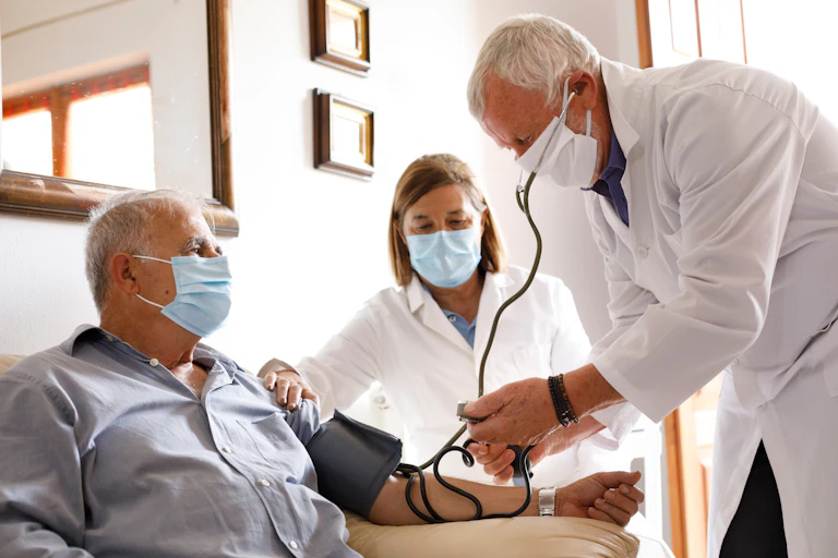 Médicos tomando la tensión a un paciente mayor.